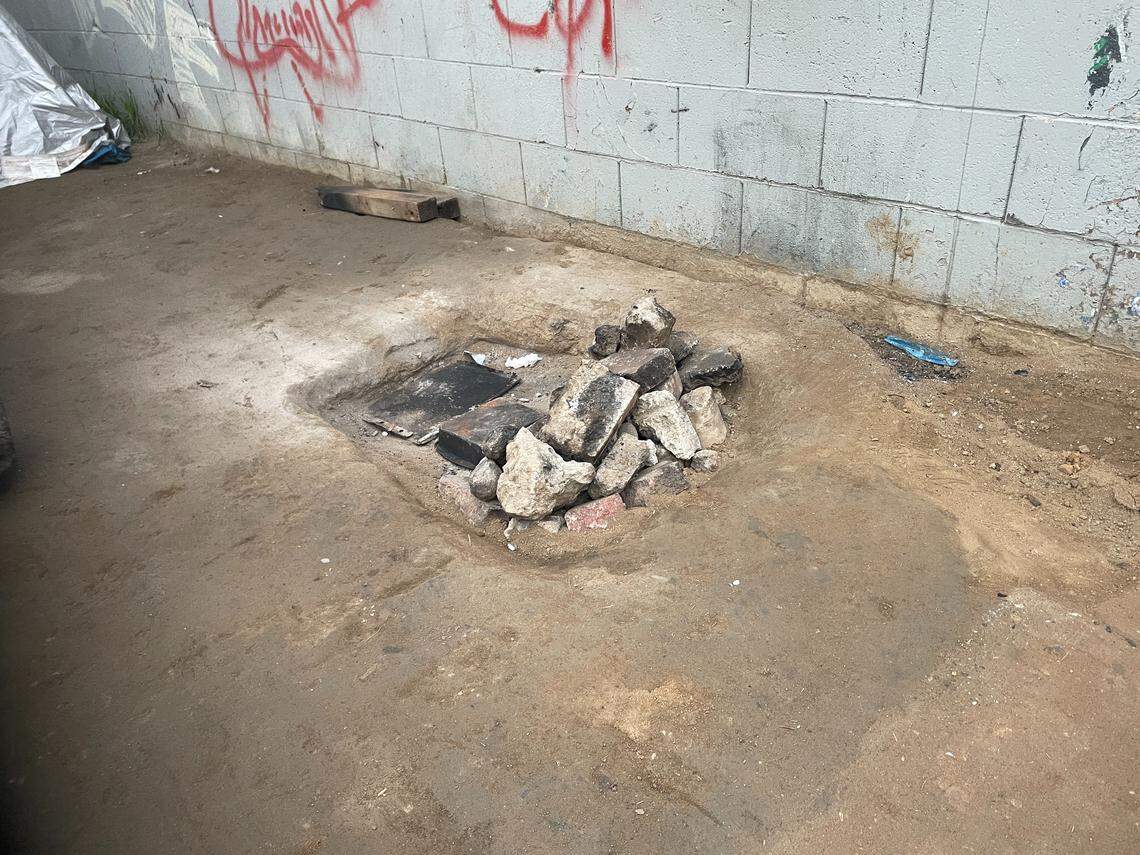An extinguished makeshift fire near a tent at the encampment near Highway 180 where two unhoused individuals died trying to stay warm. Fresno police responded to a call at the encampment on Friday, Dec. 12, 2025.