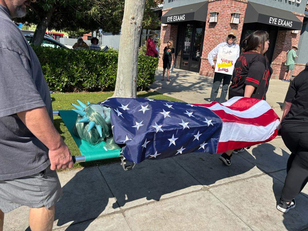 Los manifestantes portaron una obra de arte que representa a una Estatua de la Libertad fallecida cubierta con la bandera estadounidense.