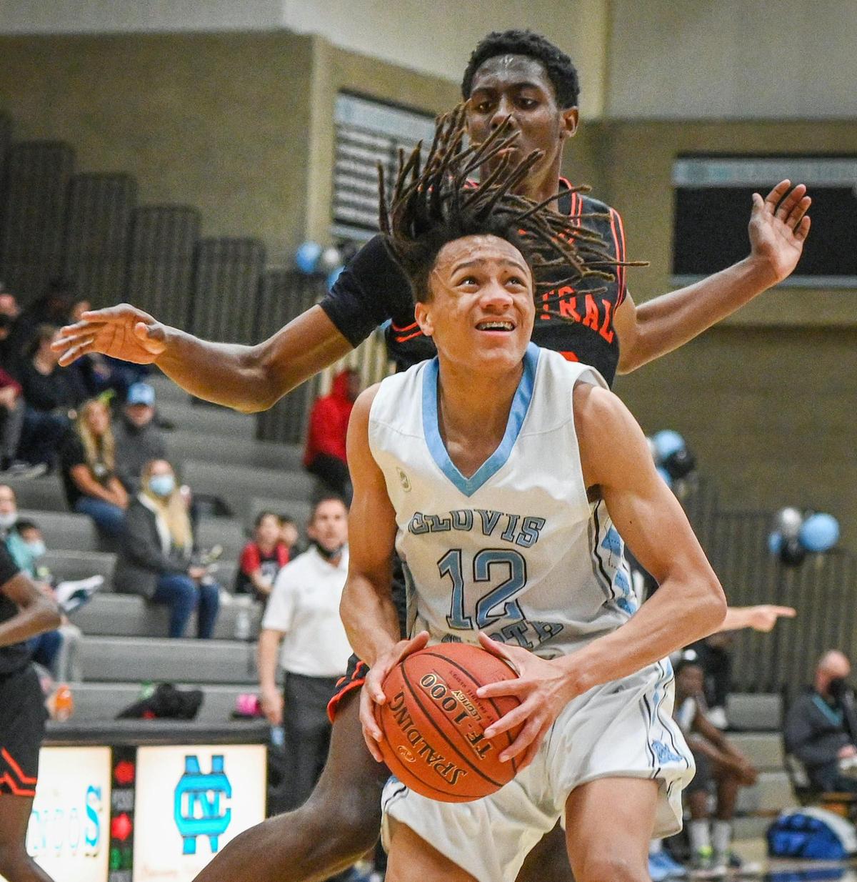 Clovis North’s Jaylen Bryant, center, looks to go to the hoop while being defended by Central’s Dylan Swillis behind him during their game at Clovis North on Friday, Jan. 21, 2022.