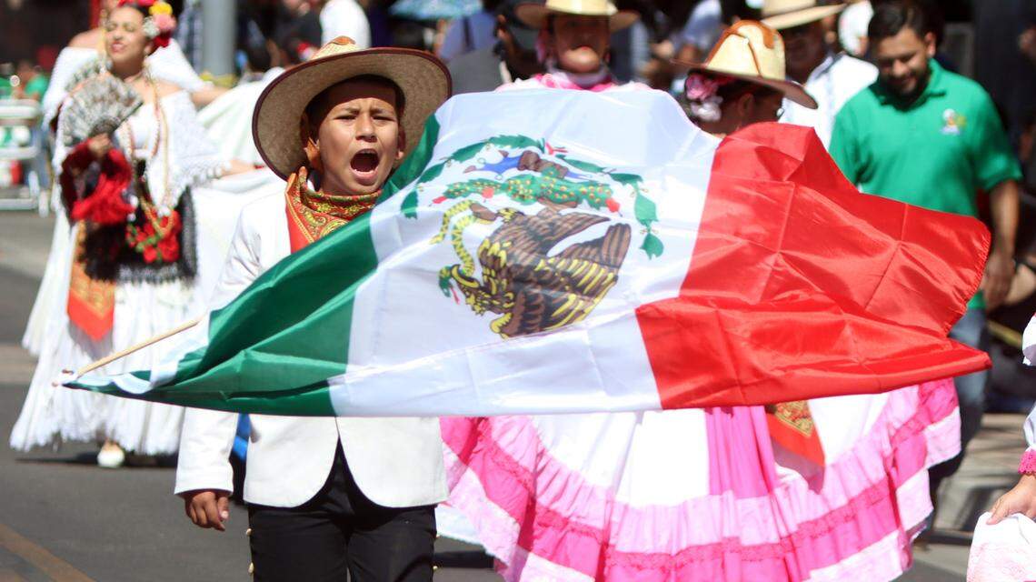 A folklórico dancer shouts as he waves the Mexican flag during the Fiestas Patrias parade at the Fulton Mall on Sept. 15, 2024. / Un danzante folklórico grita mientras ondea la bandera mexicana durante el desfile de las Fiestas Patrias en el Fulton Mall el 15 de septiembre de 2024.
