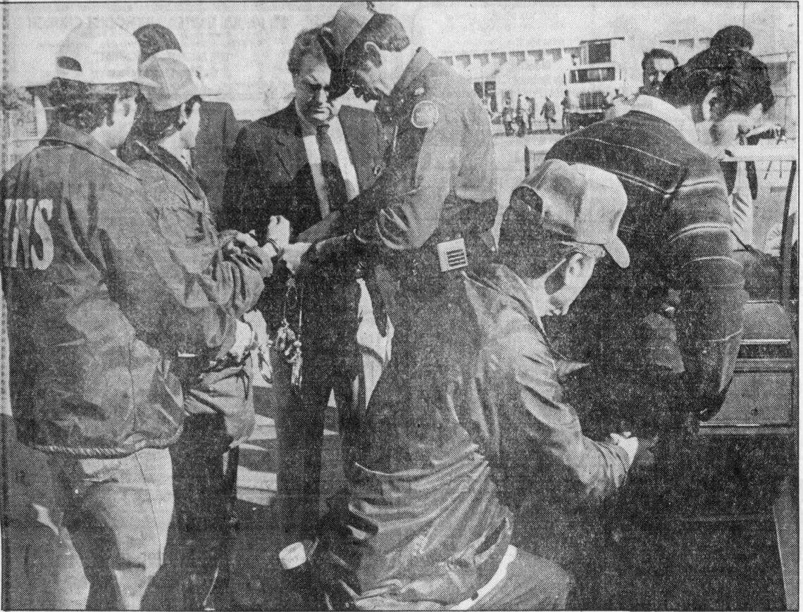 In this Fresno Bee archival photo from March 23, 1985, INS official Harold Ezell, wearing tie, watches agents handcuff undocumented individuals at Zacky Farms at 900 W. Belgravia Ave. 