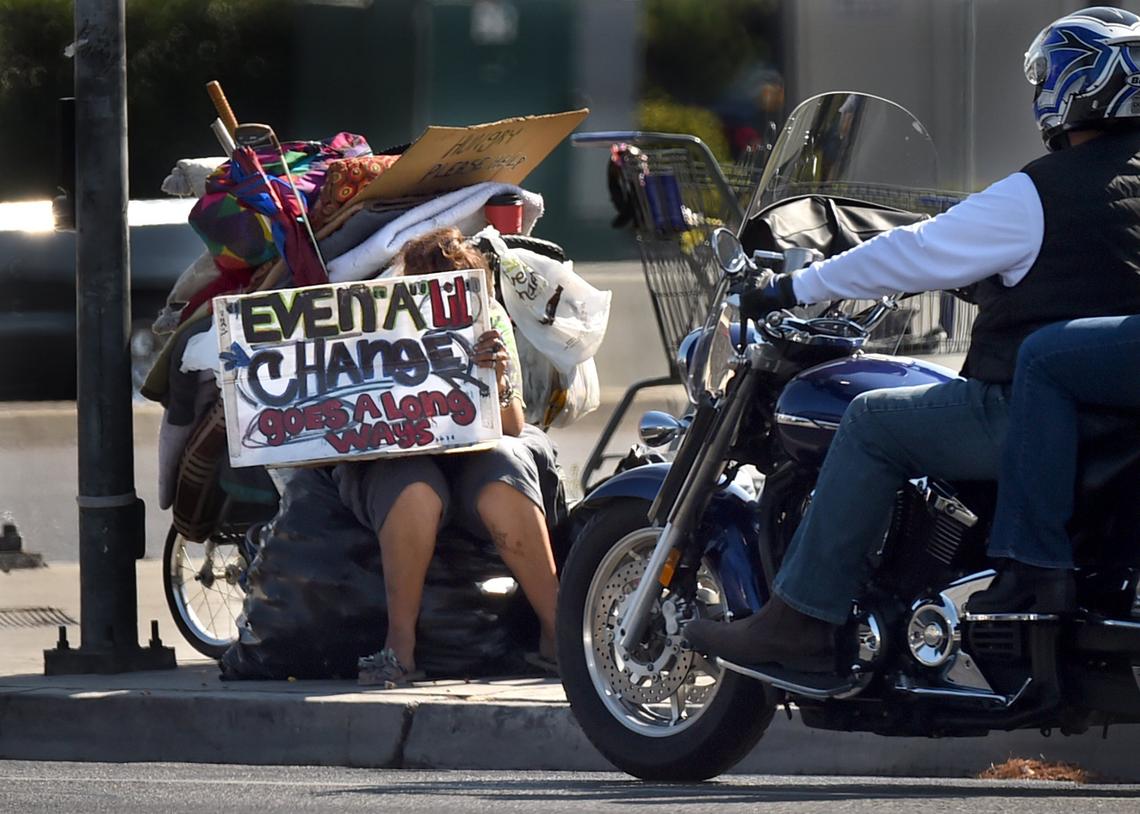 Motorists pass a woman panhandler who works a corner of Herndon and Blackstone avenues in north Fresno on Wednesday morning, July 4, 2018.
