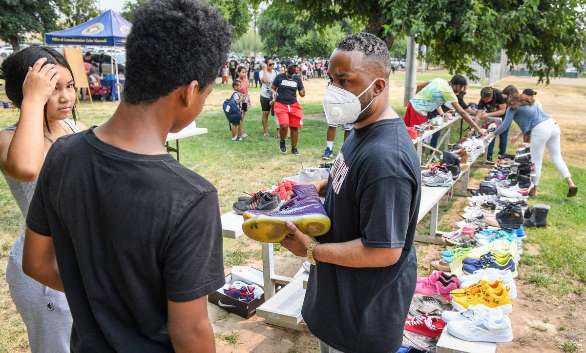 Pastor Edward Thomas, right, helps locate shoes for families at Cary Park in Fresno during the Community Kick it Outreach shoe giveaway on Saturday, Aug. 7, 2021. Thomas started the shoe giveaway with his church Living World International Church in Fresno three years ago.