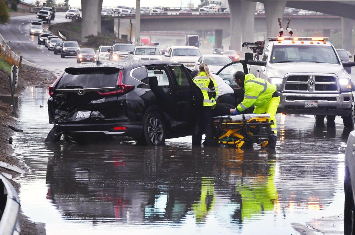 Emergency personnel attend to a passenger as southbound 41 traffic backs up merging with southbound 99 near Church Avenue after the black Honda SUV crashed in a flooded portion of the freeway Wednesday, March 10, 2021 in Fresno.