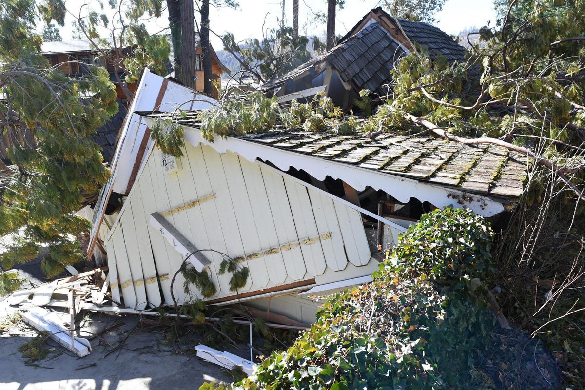 The destruction of a home crushed by falling trees is evident in the Bass Lake area after strong winds rip through the area overnight on Tuesday, Jan 19, 2021.