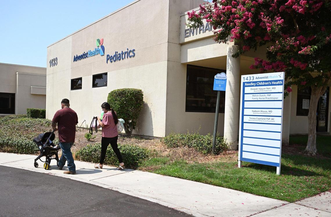 A couple with baby stroller walk away from the Adventist Health Pediatrics building Monday, July 14, 2025 in Reedley. The hospital is on the list of rural hospitals that could be endangered by funding cuts due to the ‘Big, Beautiful Bill.”