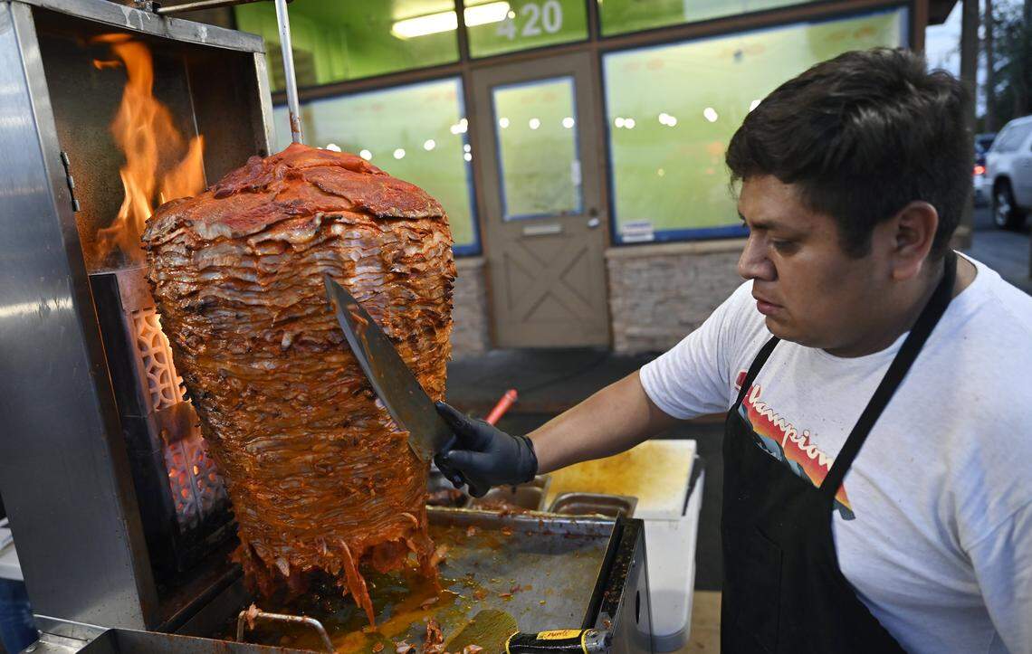 Ruben Sanchez carves al pastor off a trompo at Tacos El Cabezon, a food truck parked at the corner of Shaw and Marks avenues which has been drawing crowds to Armando Arias' Mexicali-style Mexican food with increasing social media popularity. Photographed Wednesday, Sept. 24, 2025 in Fresno.