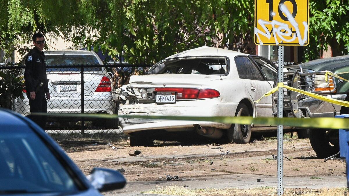 Fresno police investigate a scene at Chestnut and Lane avenues where a white vehicle, traveling at a high rate of speed, hit a garbage truck and then ended up in the yard of a residence on Thursday, Aug. 11, 2022. The driver of the white car was pronounced dead at the scene.