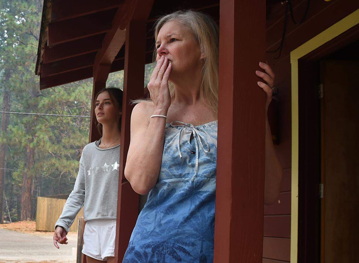 Lisa Hebert, right, looks towards vacant neighbor cabins with her daughter Lisa Hebert, left, as the family pauses while loading the family van to leave their rented cabin near Wawona Wednesday, July 25, 2018 in Yosemite National Park.