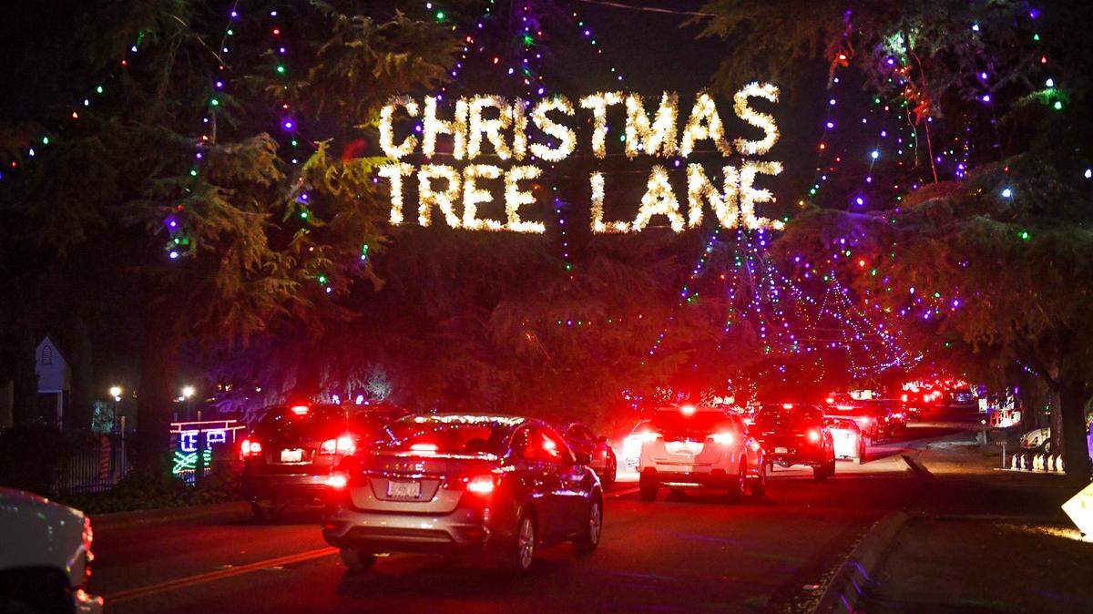 Cars pass under a sign signaling the start of Christmas Tree Lane north of Shields avenue on Tuesday, Dec. 1, 2020. The lights came on for the first time Tuesday, but for vehicle traffic only as organizers decided that keeping everyone socially distant during the pandemic prevented them from the normal walk nights.