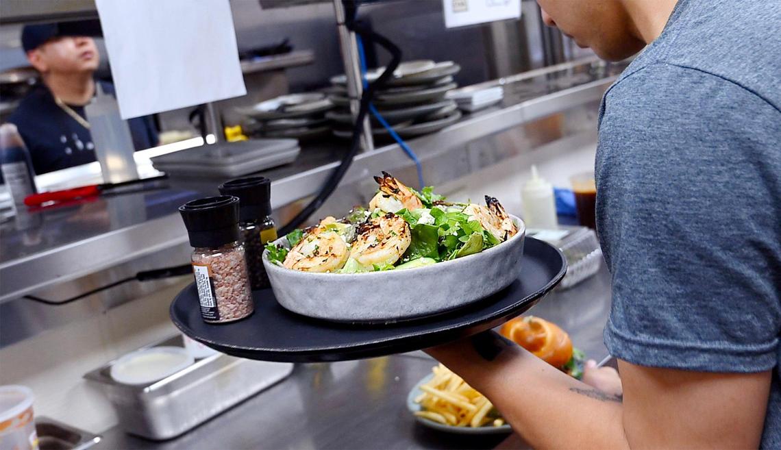 A server grabs two plates in the kitchen to serve customers.