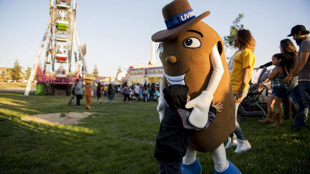 A child hugs “Moe, the sweet potato” during the annual Livingston Sweet Potato Festival at the Max Foster Sports Complex in Livingston, Calif.