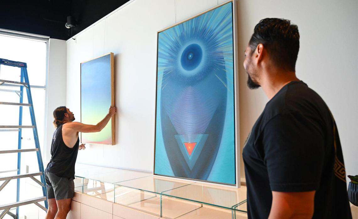 Artlounge Collective’s K. Ryan Henley, left, hangs art work as The Artist Tree’s vice president of operations Kenny Perez watches at the right, Wednesday, July 6, 2022 in Fresno. The Artist Tree is a new cannabis dispensary opening next Monday, located at Palm and Nees Avenues which will double as an art gallery once opened.
