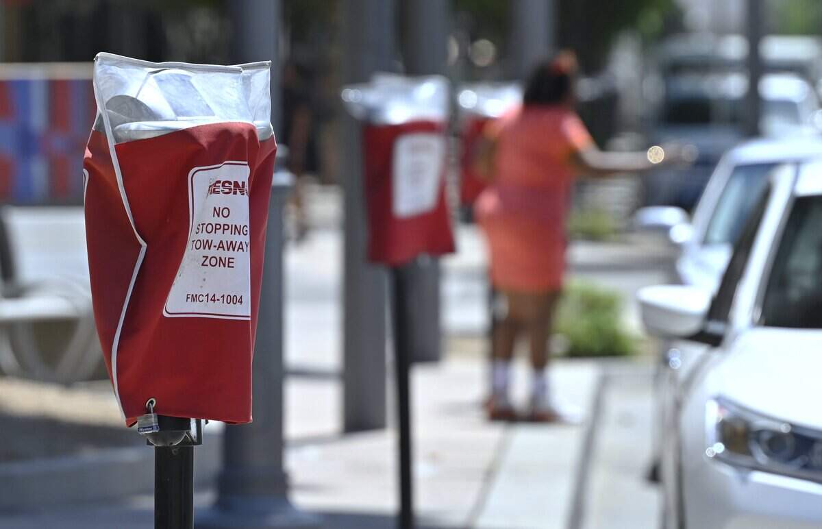 A passenger exits a car parked along Fulton Street where a row of parking meters have been covered and parking not allowed Tuesday, May 12, 2026 in downtown Fresno.