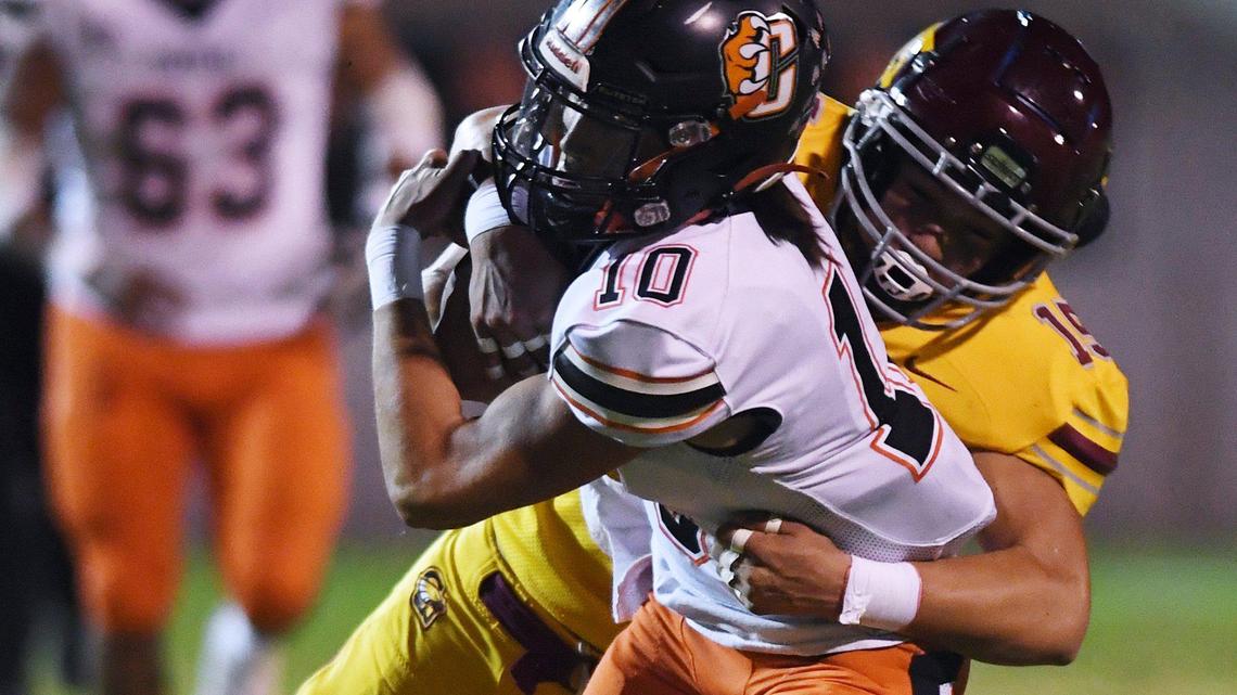 Clovis West’s Tytus Khajavi, background, tackles Central’s scramblng quarterback Dayton Tafoya, foreground, in a matchup Thursday, Oct 21, 2021 in Clovis. Clovis West pulled ahead to lead 14-13 at halftime.