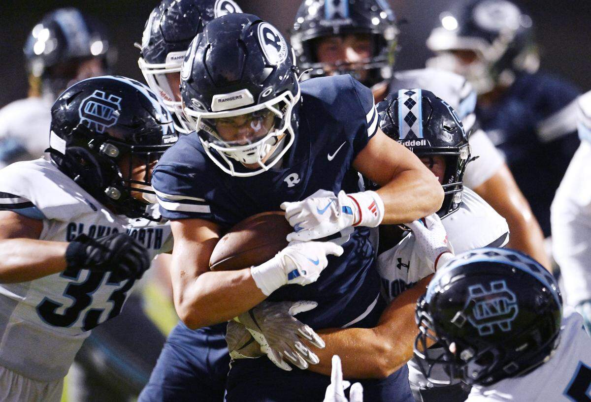 Clovis North's defense swarms Redwood High running back Jimmie Burk, center, in a game Friday, Aug. 29, 2025 in Visalia. Clovis North held off Redwood for a 38-34 win.
