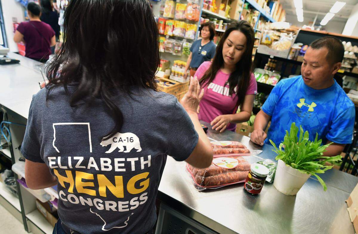 Congressional candidate Elizabeth Heng's family, including her mother, Siv Khoeu, left, at their Rasmey Market, wear t-shirts announcing her political campaign.