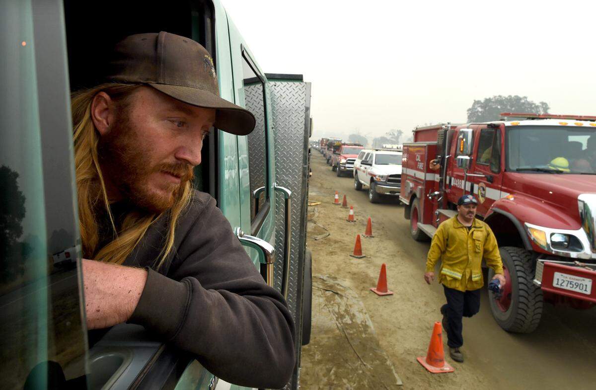 Torre Bailey, with the U.S. Forest Service, just down from the fire line, waits with dozens of other fire trucks for refueling at the fueling station set up at at the base of the highway 168 four-lane, Sept. 12, 2020.