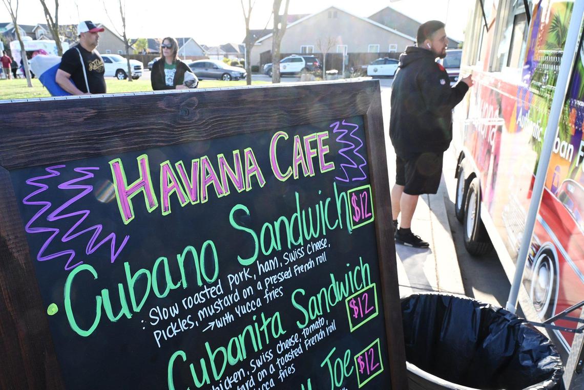 Customers begin to line up for Cuban food served at Lazaro Saldana’s new food truck Havana Cafe during a community park gathering Wednesday, March 16, 2022 in Fresno. Lazaro and his wife Niermin Santana have opened a food truck staffed by family members which specializes in Cuban food and coffee.