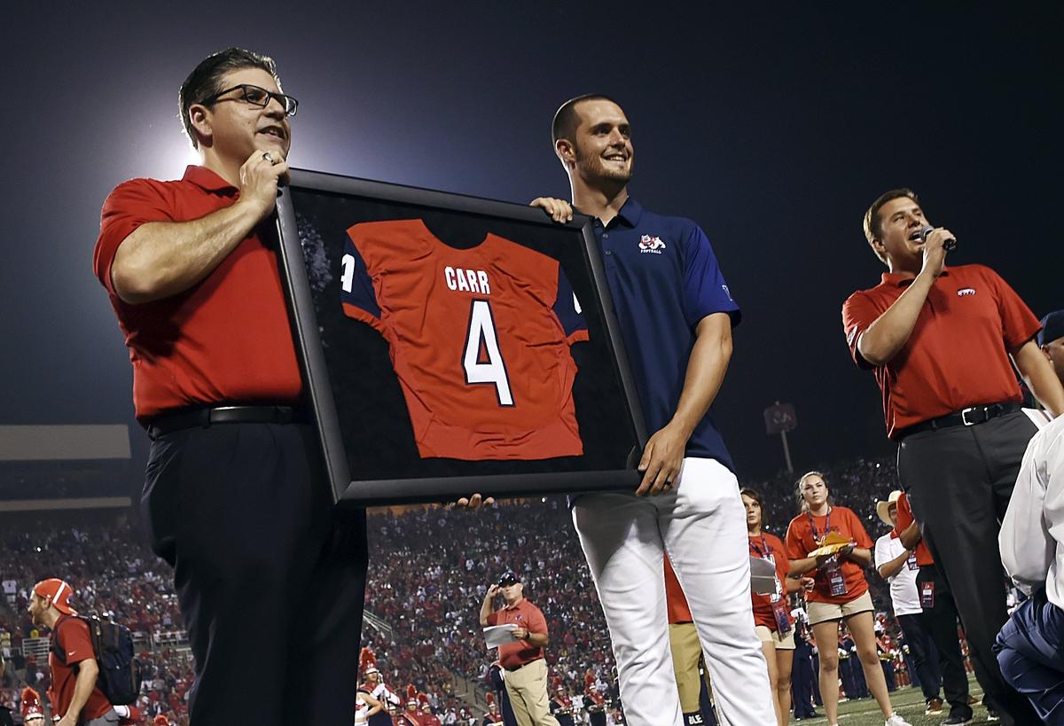 Fresno State president Joseph I. Castro, left, poses with Derek Carr and Carr’s retired framed No. 4 jersey during haltime in the Bulldogs’ season home opener against Incarnate Word Saturday, Sept. 2, 2017 in Fresno.