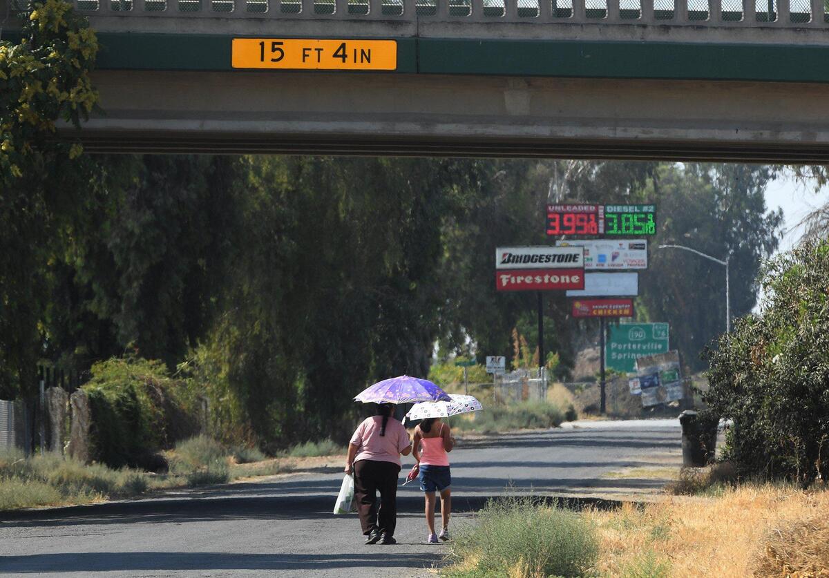 Two people walk under a freeway overpass in Tipton on July 29, 2021.