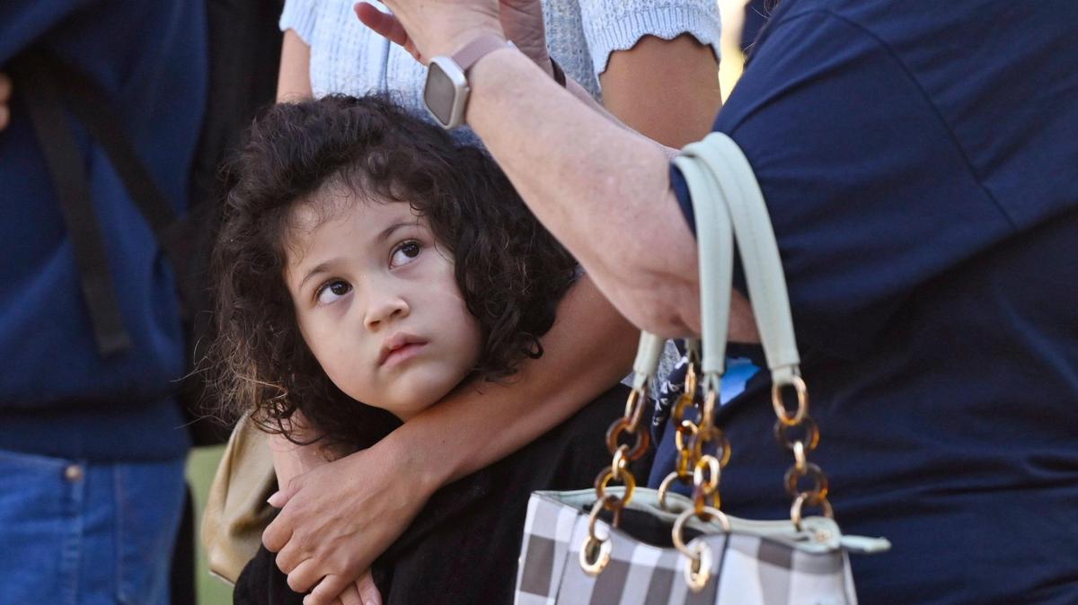 Lily Wichapool, 5, looks across to protesters as she stands in the arms of her mother Desiree Ledezma as the city of Fresno raised an Israeli flag in solidarity with Israel in a ceremony at Eaton Plaza Thursday, Oct. 12, 2023 in downtown Fresno. Lily and her mother attend Temple Beth Israel.