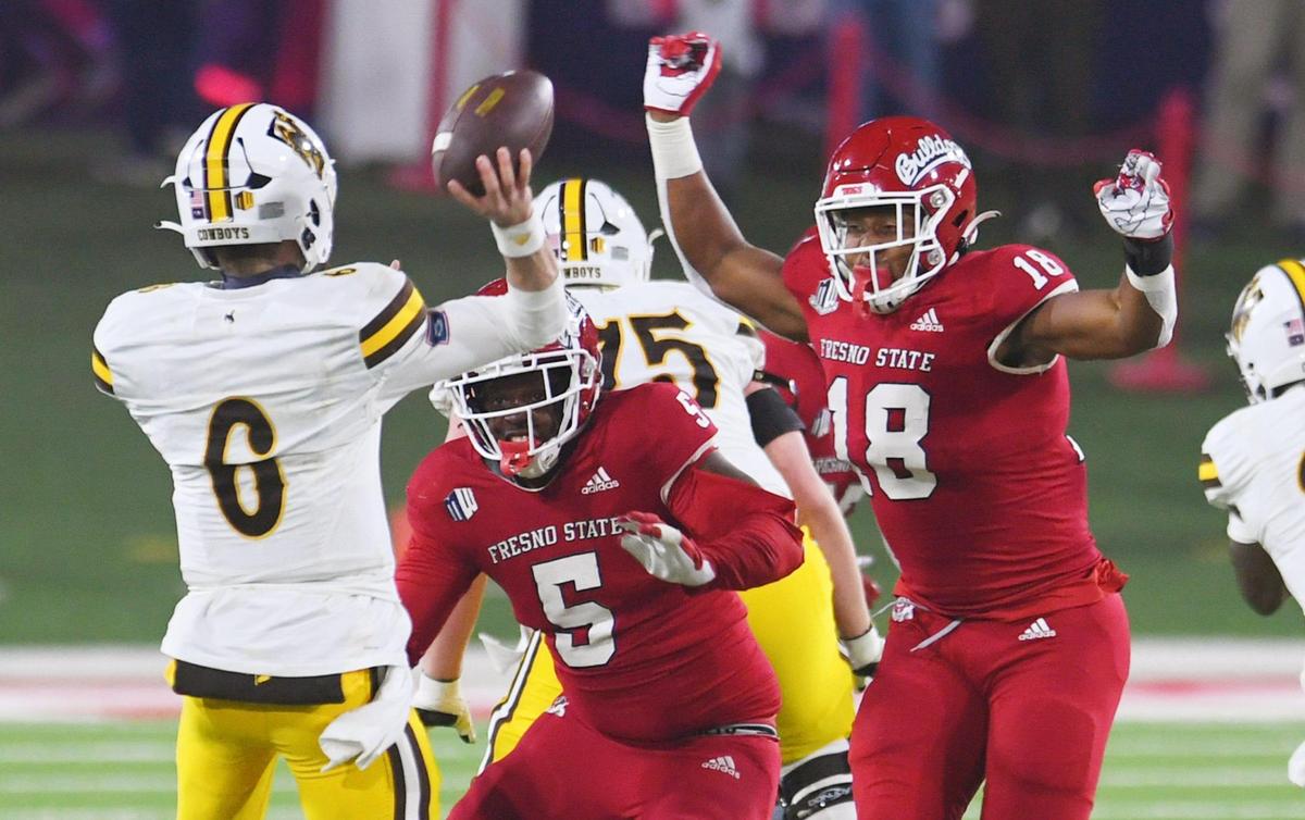 Fresno State’s Devo Bridges, center, and Isaiah Johnson, right, pressure Wyoming quarterback Andrew Peasley, left, in game action Friday, Nov. 25, 2022 in Fresno. The Bulldogs led 23-0 at halftime.