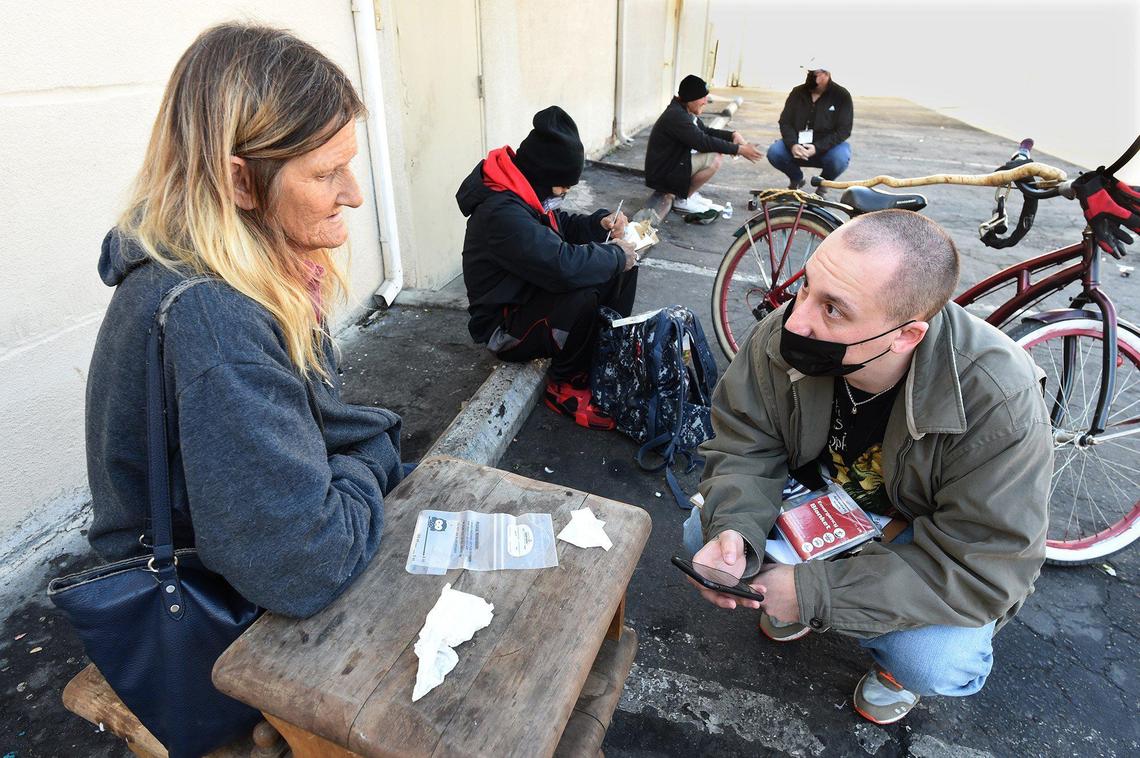 Volunteer Dylan Jenkins conducts a Point in Time count survey for the Fresno Madera Continuum of Care with homeless Fresno native Barbara Anderson, in the Tower District, Feb. 25, 2022.