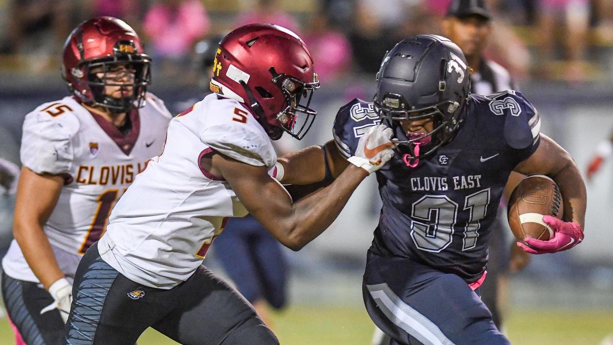 Clovis East running back Caleb Slocum gets his face mask yanked by Clovis West’s Marshel Sanders on a run during their game at Lamonica Stadium on Friday, Oct. 7, 2022.