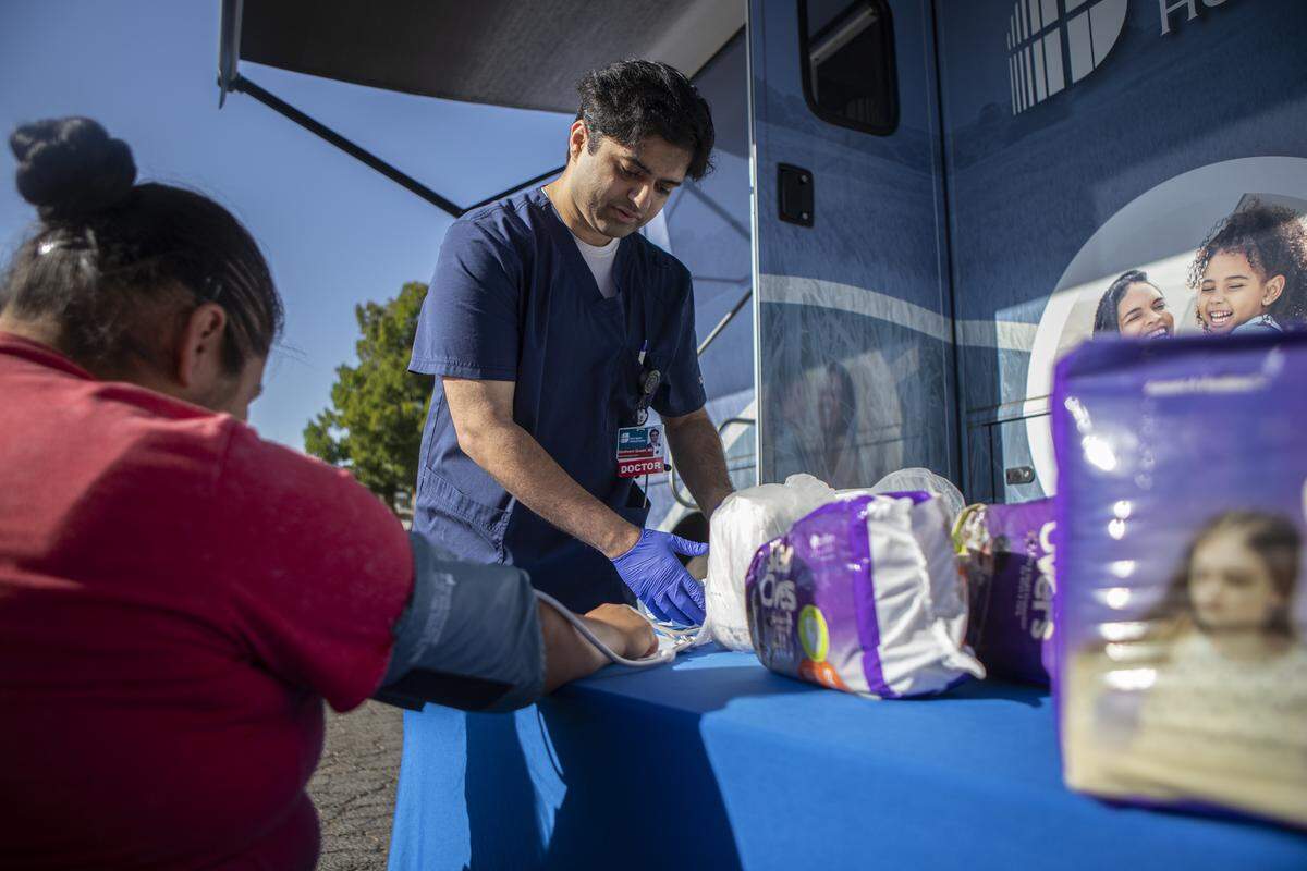 Dr. Ebraheem Quadri examines a patient in the parking lot outside the Saint Agnes Mobile Health Unit clinic, located in Rojas Pierce Park in Mendota on Aug. 28, 2025. Photo by Larry Valenzuela, CalMatters/CatchLight Local