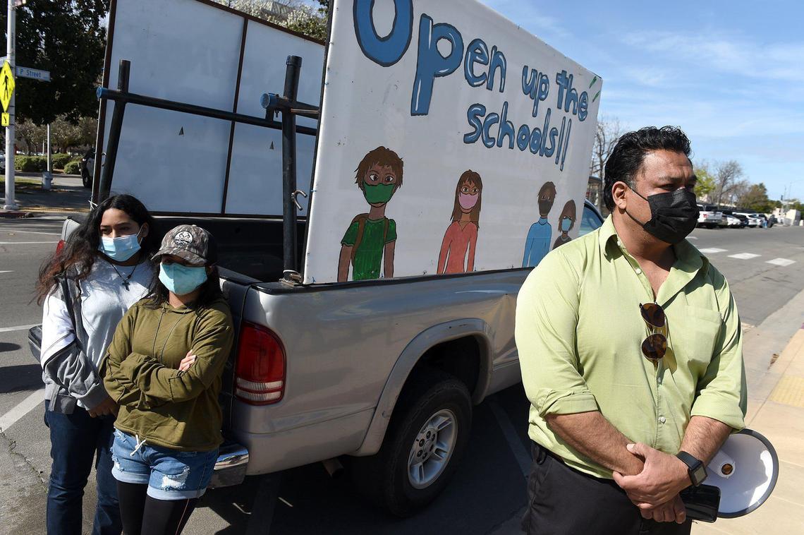 Juan Esquivel, with daughters Shayla, left, and Virginia, stand by their pickup at the Save Our Kids rally on Saturday, March 6, 2021, at Fresno City Hall. Virginia, Juan said, stayed up all night painting the signs for the truck ahead of the rally to promote reopening Fresno Unified schools amid the coronavirus pandemic. She pointed out that she was proud of herself, not having had an art lesson. Both girls are in Fresno Unified.