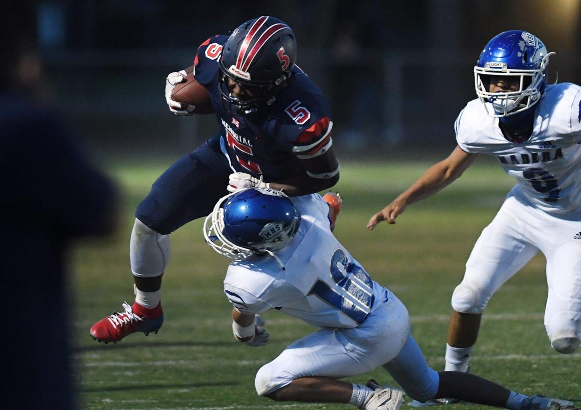 San Joaquin Memorial’s Jordan Hornbeak, left, is tackled on a run by Madera’s Chris Marquez, bottom, Friday, April 30, 2021 in Fresno.