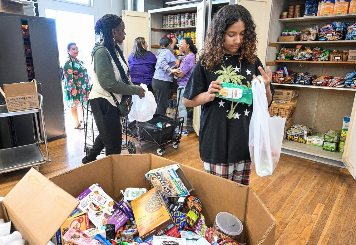 Naila Sightler, right, a Fort Miller Middle School seventh grade transfer student, packs up food during the School’s Community School Food Pantry & Clothing Closet event at the Fresno school on Friday, March 8, 2024.