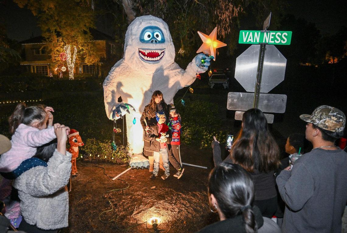 Holiday revelers stop to take photos next to a giant abominable snowman from the 1964 movie “Rudolph the Red-Nosed Reindeer” on the first of two walk-only nights on Tuesday, Dec. 3, 2024.
