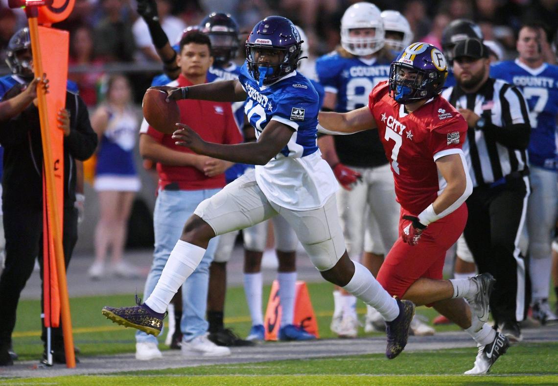 Washington Union quarterback Lawrence Stell, playing for County, scrambles away from Fresno’s Bryan Guerrero, left, playing for City at the City/County All-Star football game held at McLane High’s stadium Friday night, June 17, 2022 in Fresno. The game ended 21-21.