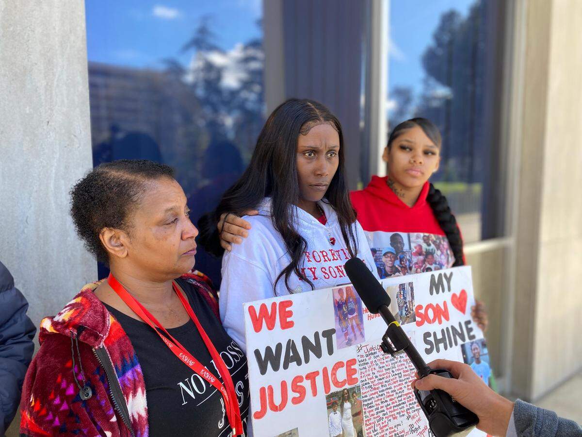 Ragina Bell, the mother of Rashad Al-Hakim Jr. is flanked by Monique Lewis, left, and Nevaeh Solomon, right, on Wednesday, Feb. 21, 2024, outside the Fresno County Courthouse.