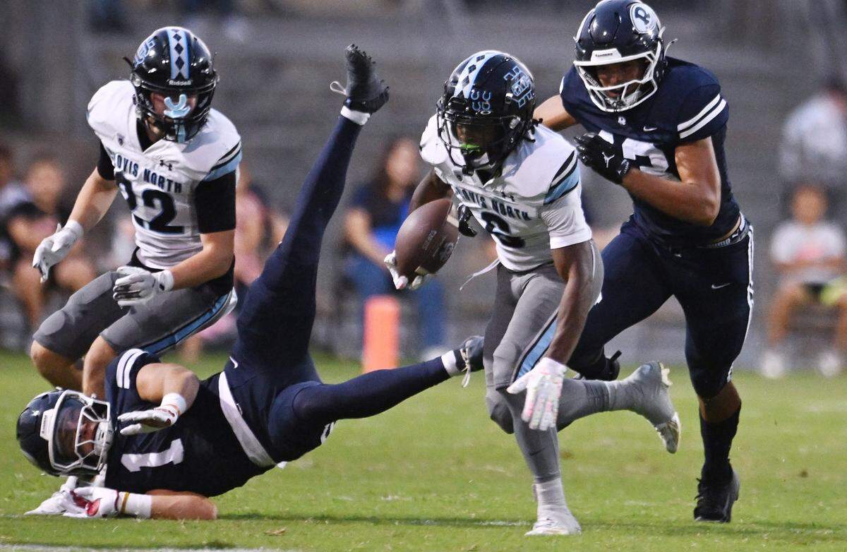 Clovis North's Tyree Sams, center, runs against Redwood High in a game Friday, Aug. 29, 2025 in Visalia. Clovis North held off Redwood for a 38-34 win.