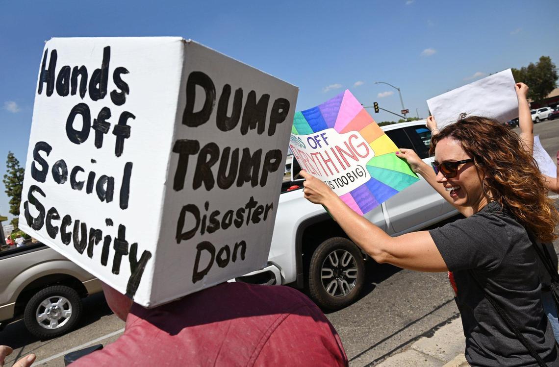 Lindsay Folmer, right, laughs with retired FUSD teacher Ed Parrish to the left during a Hands Off rally at Clovis and Shaw avenues Saturday, April 19, 2025 in Clovis.
