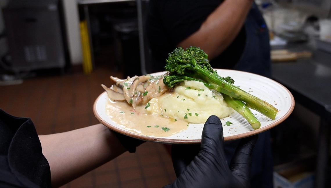 A plate is moved from the kitchen to a customer at a local restaurant.