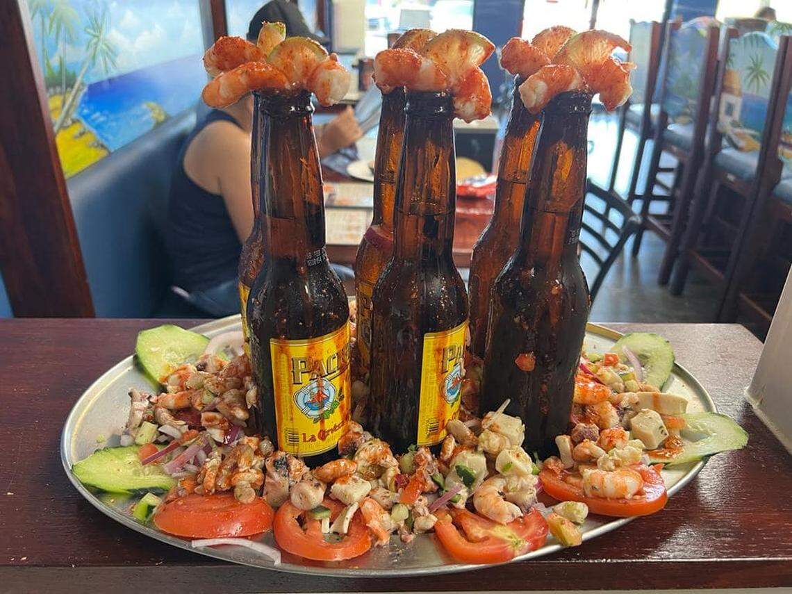 Some of their alcoholic drinks come at Mariscos El Barba Negra come in a bright, orange-reddish color, like the micheladas, the cervezas preparada. and a bottle of Corona drizzled with red chamoy with a shrimp on top.