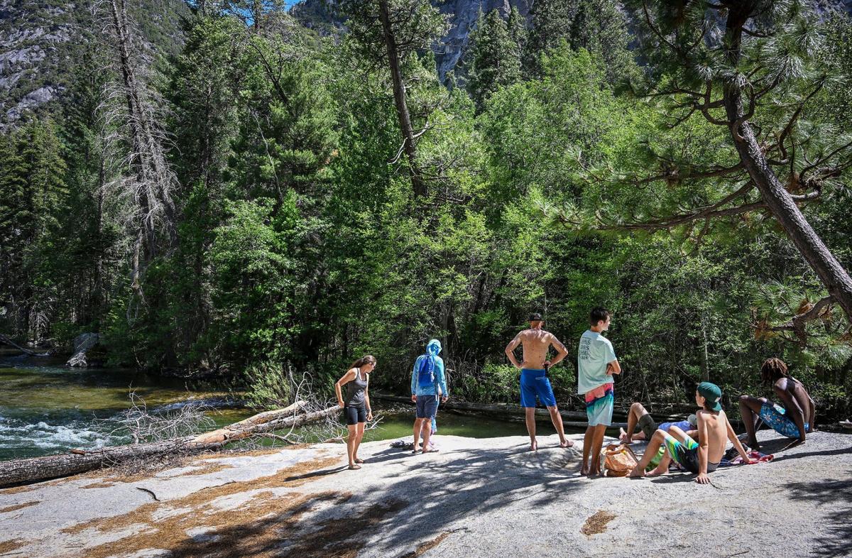 Vacationers relax while taking in the views of the south fork of the Kings River at Muir Rock in Kings Canyon National Park’s Cedar Grove on Tuesday, June 11, 2024.