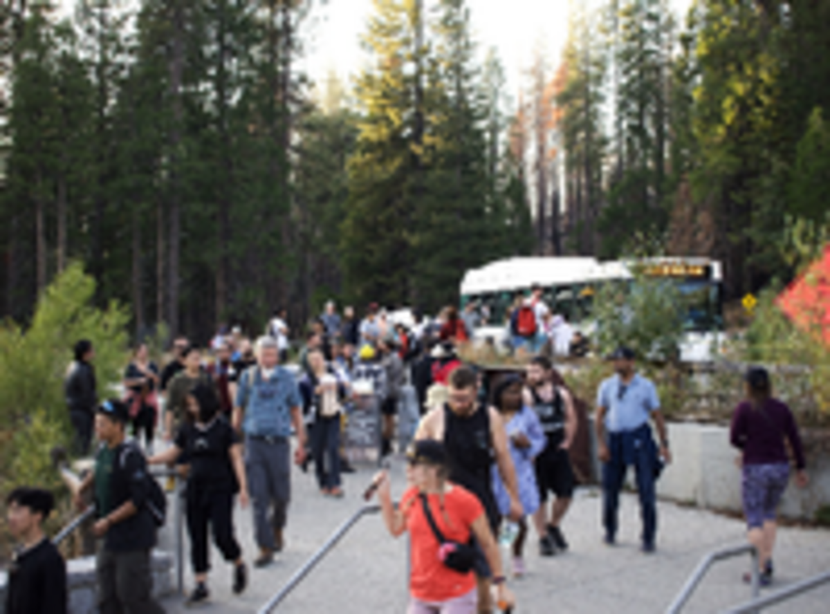 Dozens of tourists step out of a shuttle bus just inside Yosemite National Park’s south entrance. Visitors might not have access to services and facilities in the park if it closes.