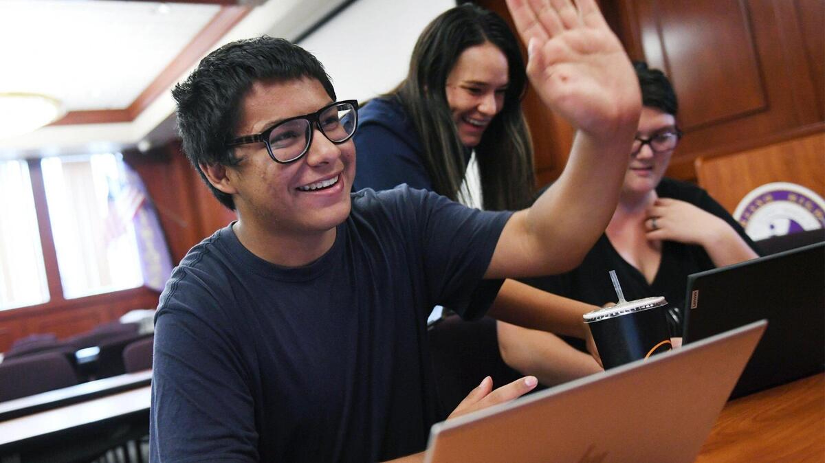Fresno High student Victor Rivera, left, raises his hand for a high-five as he sees over $1,000 in his CalKIDS account for college Wednesday, Aug. 17, 2022 in Fresno.