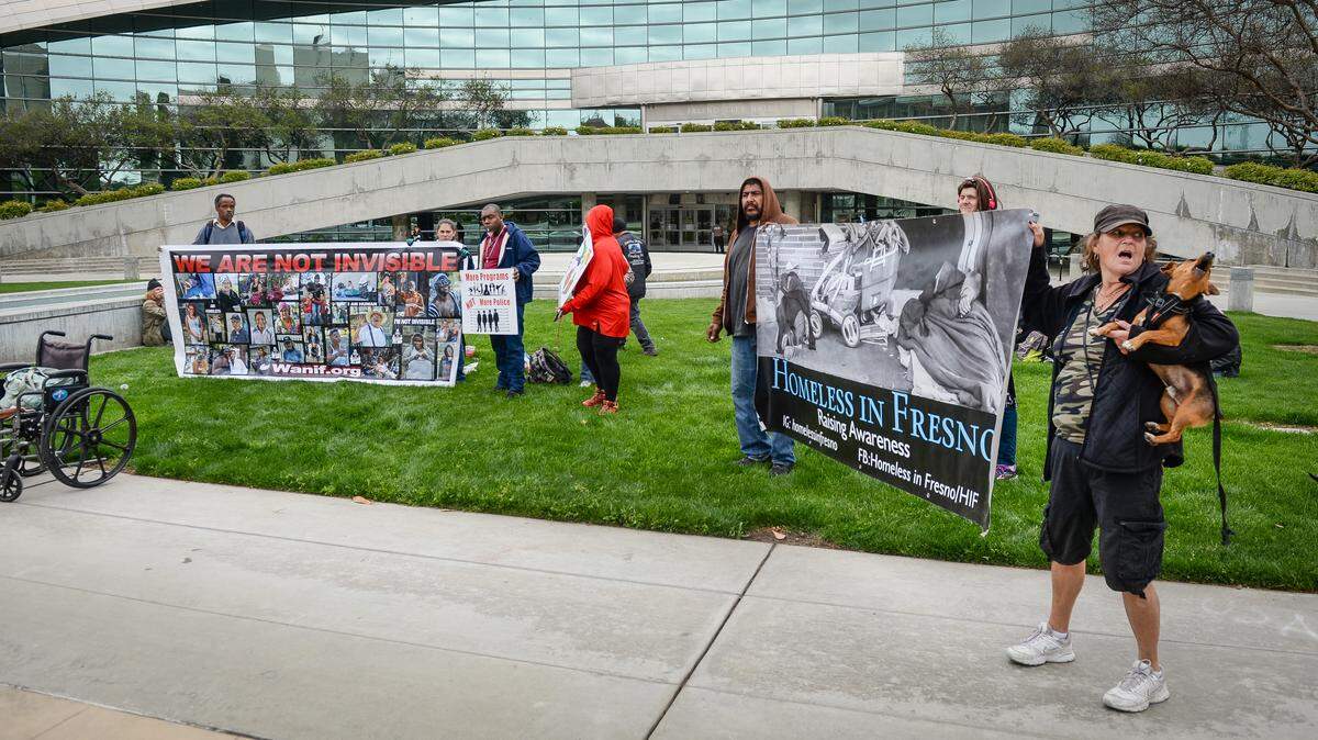 Homeless people and advocates stand with signs outside of Fresno City Hall to raise awareness and push for additional help from the governor’s emergency homeless grant. The group was also asking for help with portable restrooms and washing stations to combat the coronavirus pandemic.