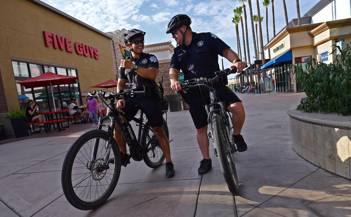 Fresno police officers Luke Tran, left, and Dustin Freeman, right, prepare to continue their patrol of River Park late Saturday afternoon, July 30, 2022 in Fresno.