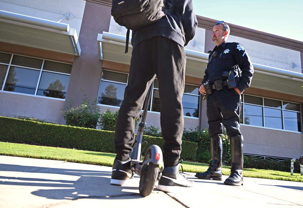Fresno Police traffic officer Jason Hurley addresses a Clovis West student with the law regarding riding e-scooters on sidewalks Thursday morning, May 21, 2026 in Clovis.