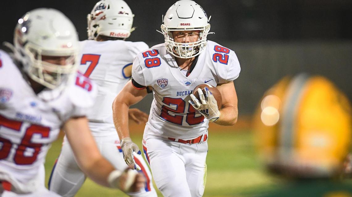 Buchanan’s Caden Rodgers, center, waits for blocking before charging though the scrimmage line on a run up the middle during their game against Kingsburg at Kingsburg High on Friday, Aug. 20, 2021.