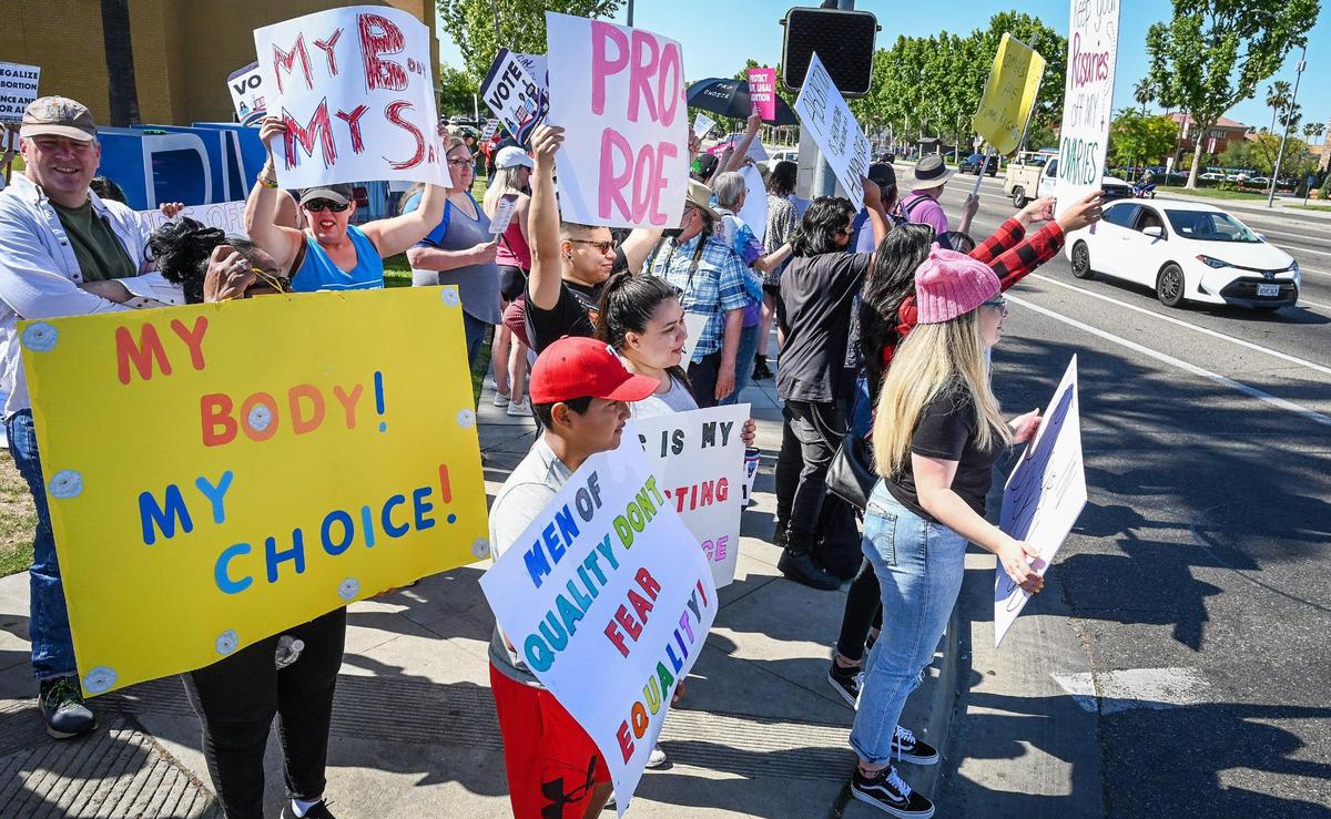 Protesters stand on the corner of Blackstone Avenue at Nees near the River Park shopping center in Fresno during a rally in support of Roe v. Wade on Saturday, May 14, 2022.