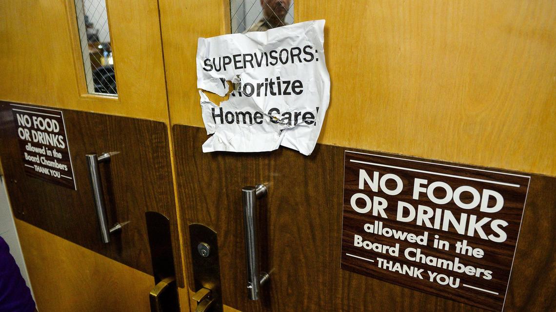 A deputy watches through the Fresno County Board of Supervisors chambers doorway as protestors in the hallway argue for better pay for county caregivers, on Tuesday, Aug. 20, 2019.