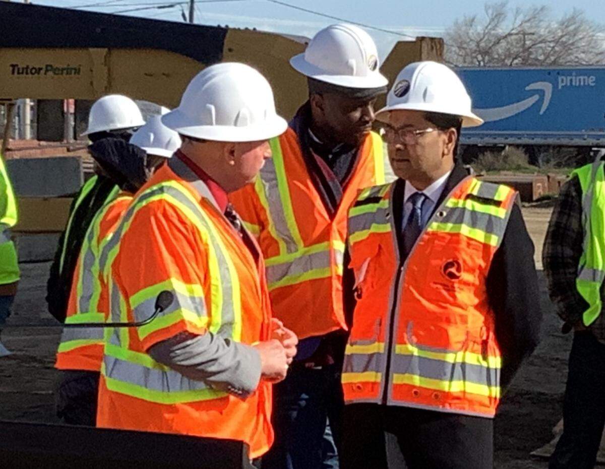 Fresno Mayor Jerry Dyer, left, talks with Federal Railroad Administration chief Amit Bose on Tuesday, Feb. 14, 2023, at the construction site of a high-speed rail viaduct over Cedar Avenue and Highway 99 in south Fresno. Toks Omishakin, secretary of the California State Transportation Agency, stands behind the two.